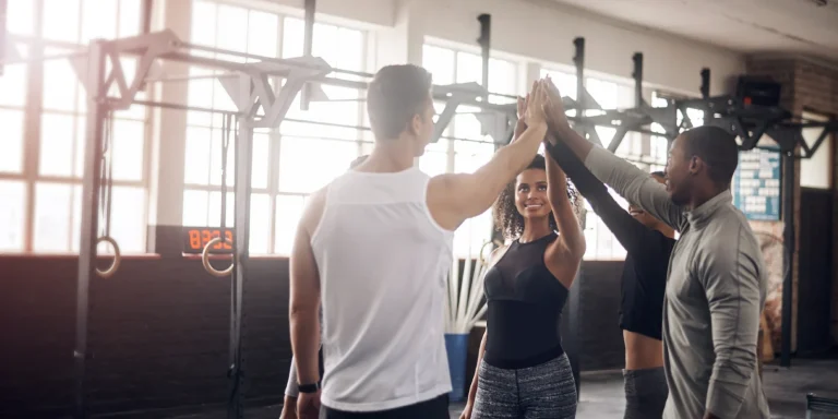 group of fitness friends doing a high five at the gym